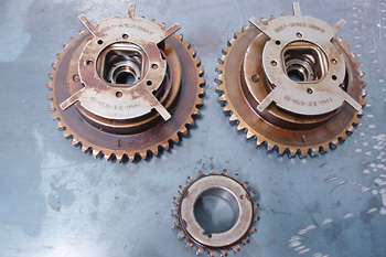These camshaft sprockets and timing gears are integral parts on this Ford application. The stamped steel plates are reluctors that allow the camshaft position sensor to sense valve timing. A conventional timing chain sprocket completes the set.