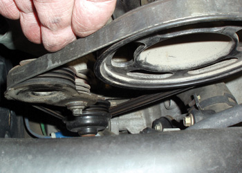 the epdm serpentine drive belt on this 3.0l ford water pump is hidden under the engine cover at the rear of the front cylinder head. note the spring-loaded tensioner.