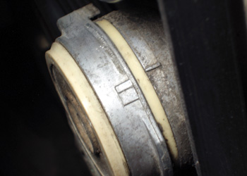 The index marks on this belt tensioner match when the belt is new and separate as the belt wears. Wear in the plastic pivot bushings might cause a rattling noise with the engine running.
