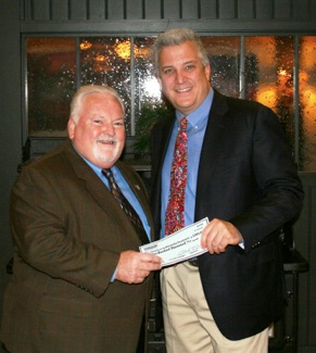 Steve Berman (at right), chairman and CEO of Dorman Products Inc., presents a check to University of the Aftermarket Foundation Secretary John Washbish. 